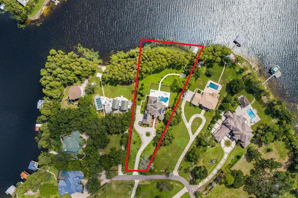An aerial view shows a waterfront house with a pool inside a red property boundary — 9412 EDDINGS ROAD, ODESSA, FL