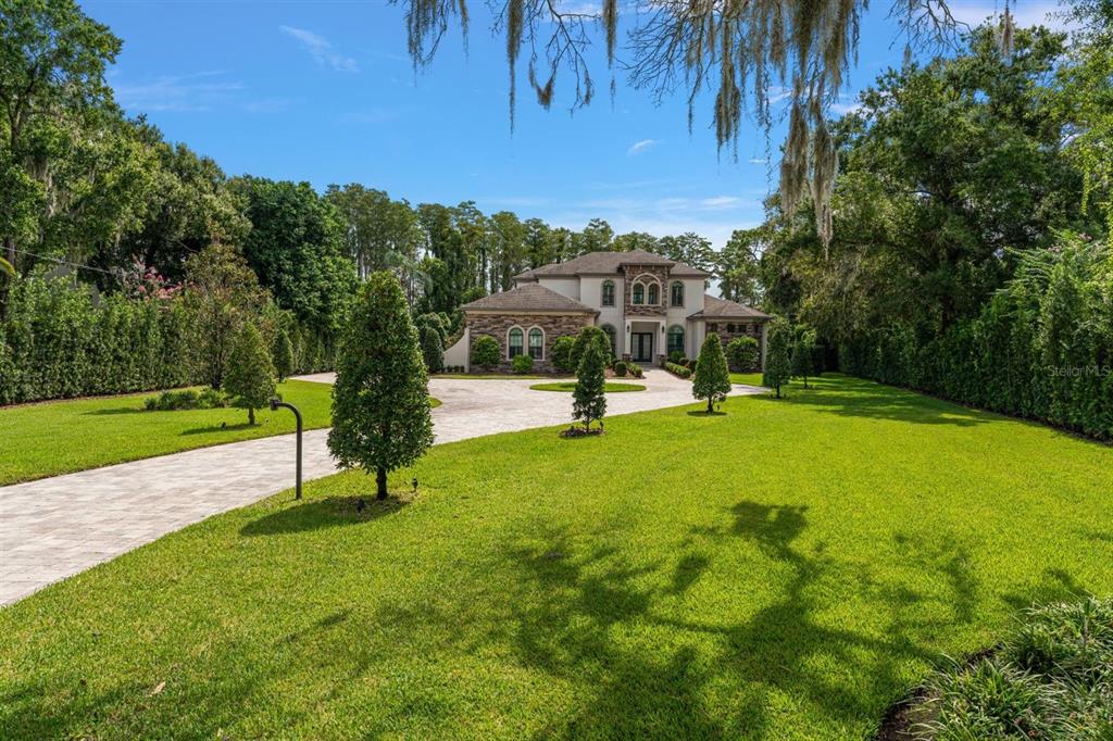 A large two-story house with a stone facade sits at the end of a paved driveway — 9412 EDDINGS ROAD, ODESSA, FL