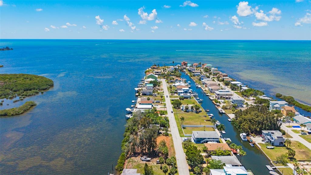An aerial view shows a residential peninsula surrounded by water with a central road — 6646 SEAVIEW BOULEVARD, HUDSON, FL