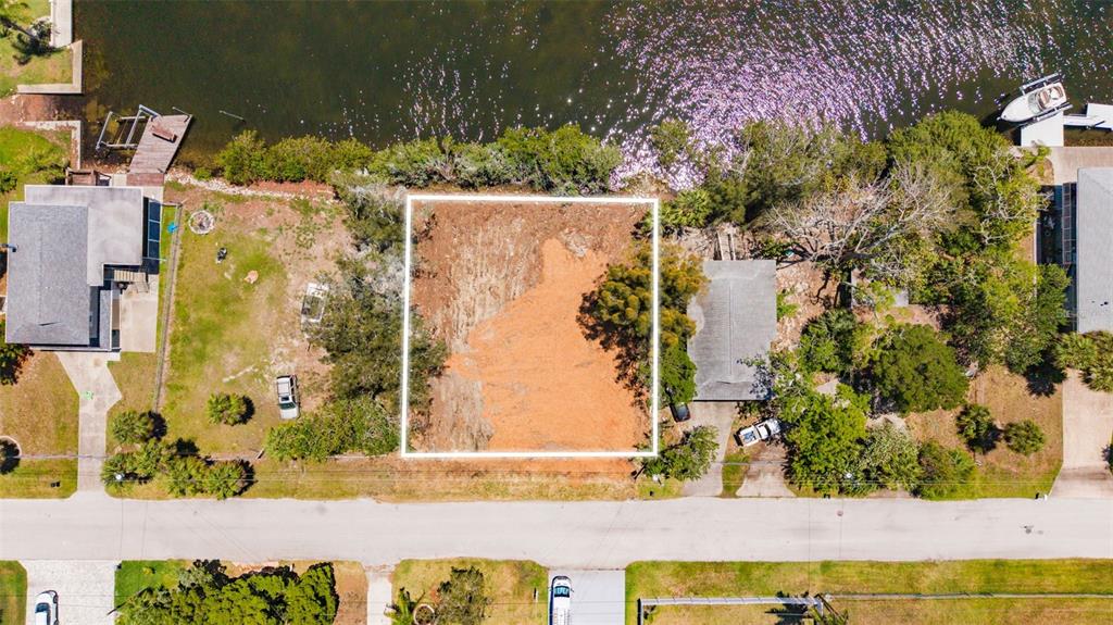 An aerial view shows a cleared, rectangular vacant lot situated between two houses along a waterfront — 6646 SEAVIEW BOULEVARD, HUDSON, FL