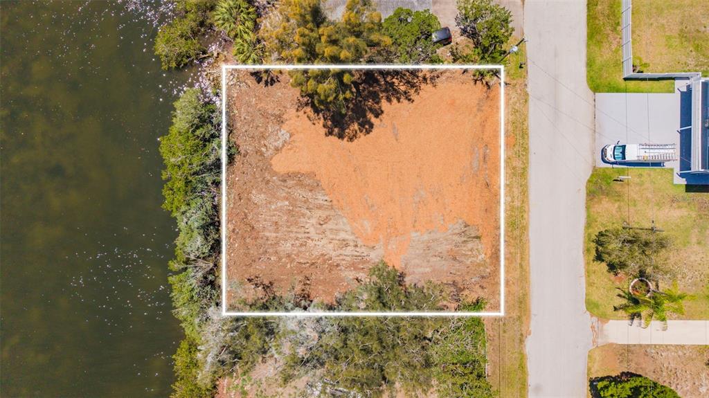 An aerial view shows a cleared, rectangular waterfront lot outlined in white next to a road — 6646 SEAVIEW BOULEVARD, HUDSON, FL