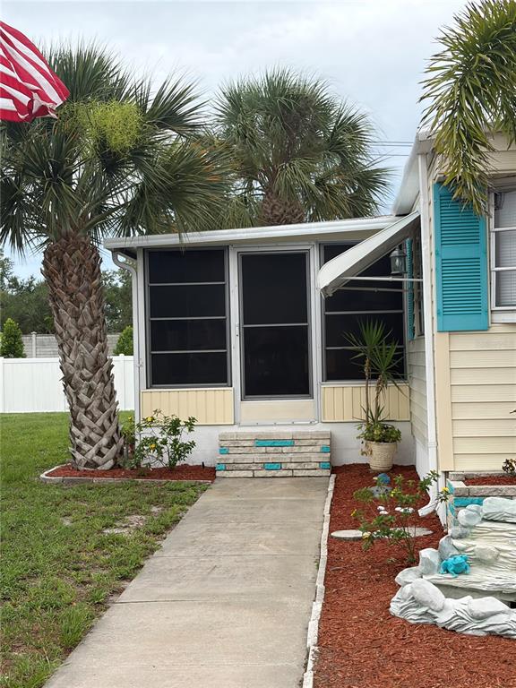 A concrete walkway leads to the screened-in porch of a mobile home with palm trees — 723 ROMA ROAD, VENICE, FL