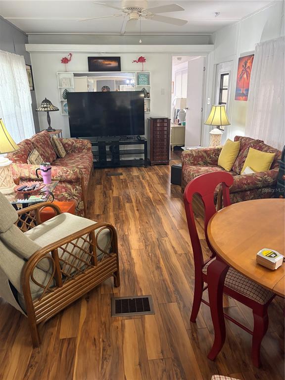 A living room features floral sofas, a rattan chair, a television, and wood-look flooring — 723 ROMA ROAD, VENICE, FL