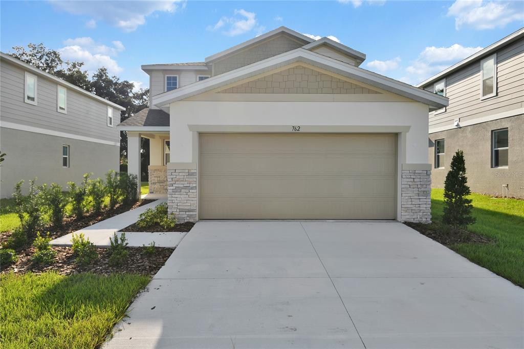 A two-story suburban house features a beige garage, stone accents, and a concrete driveway — 762 LAKE DELL AVENUE, DUNDEE, FL