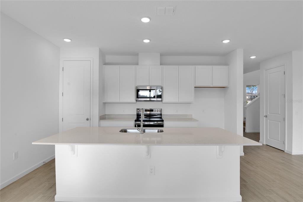 A modern kitchen features white cabinetry, a large island with a sink, and stainless appliances — 762 LAKE DELL AVENUE, DUNDEE, FL