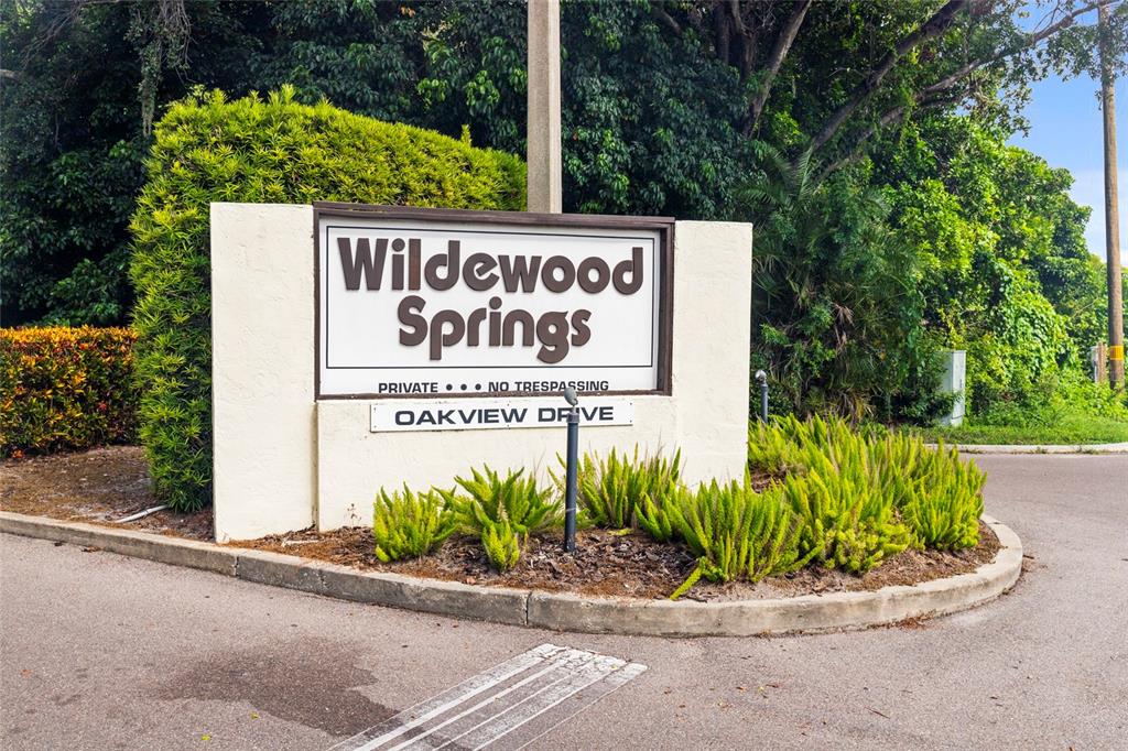 A sign for Wildewood Springs stands at the entrance to Oakview Drive near lush foliage — 440 PALM TREE DRIVE UNIT N/A, BRADENTON, FL
