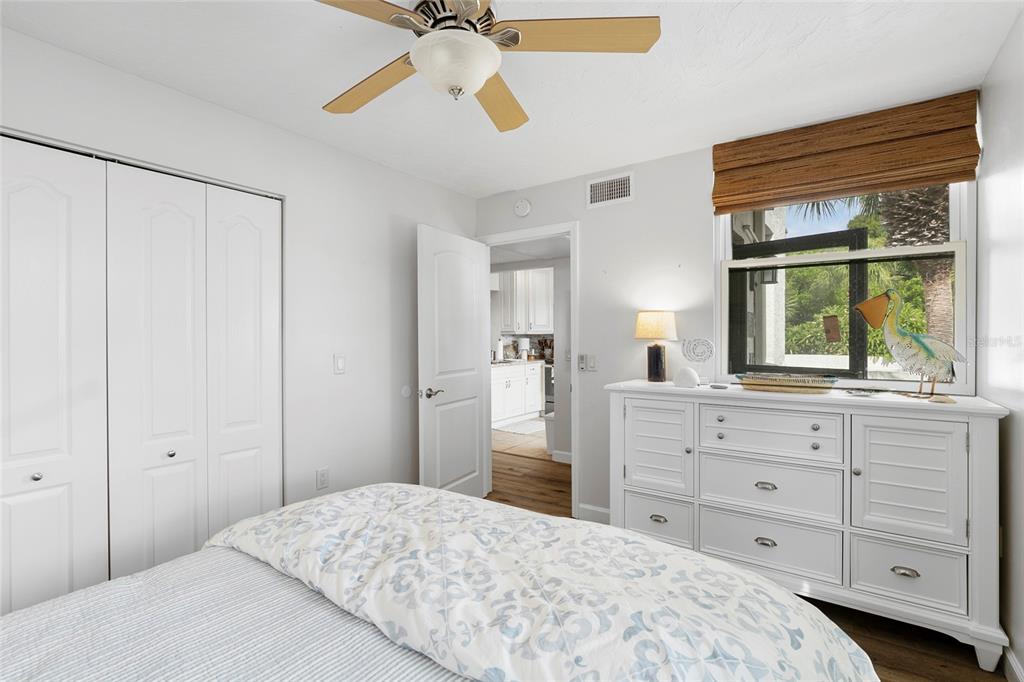 A bedroom features a white dresser, a ceiling fan, and a view into a kitchen — 440 PALM TREE DRIVE UNIT N/A, BRADENTON, FL
