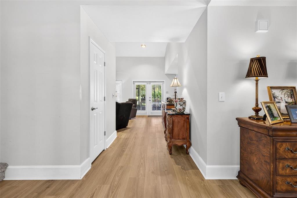 A hallway with light wood flooring leads toward a room with French doors — 7217 RIDGEPORT DRIVE, TAMPA, FL