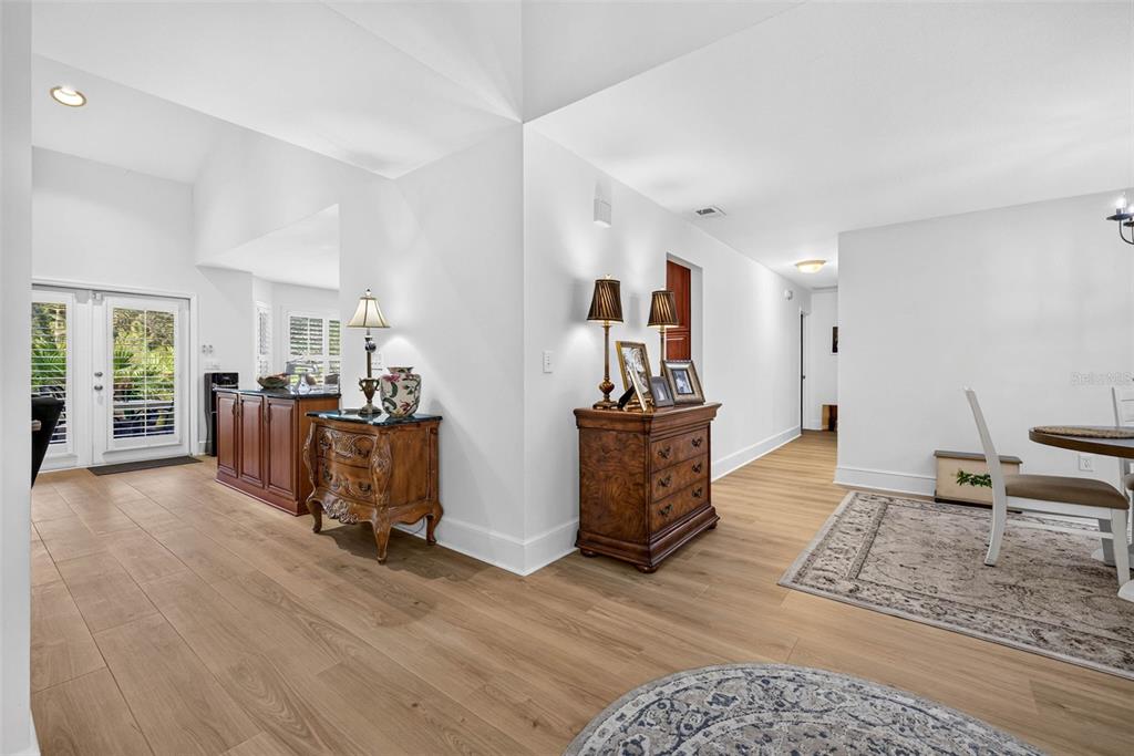 A bright, open-concept living area features light wood flooring, white walls, and traditional wooden furniture — 7217 RIDGEPORT DRIVE, TAMPA, FL