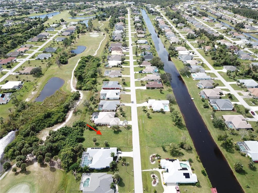 An aerial view shows a vacant residential lot situated between two houses near a canal — 54 MARKER ROAD, ROTONDA WEST, FL