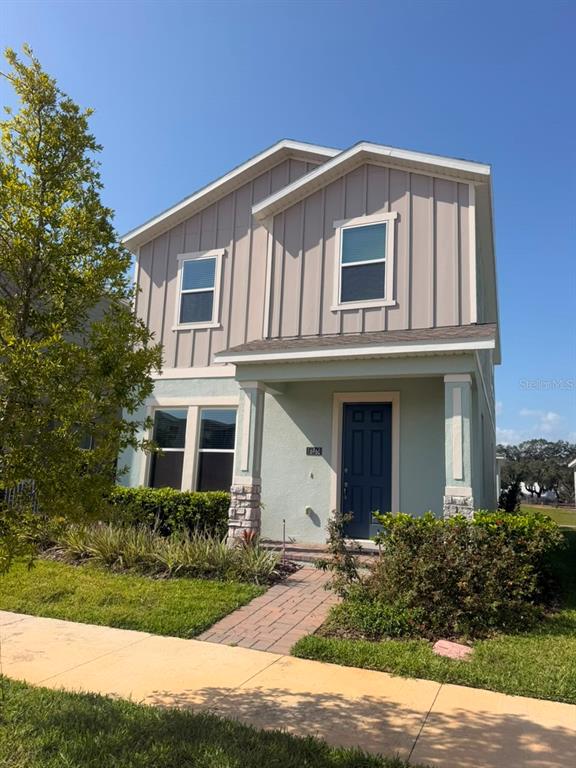 A two-story house with light-colored siding, a stone-accented porch, and a dark blue front door — 16968 HAMLIN OASIS LOOP, WINTER GARDEN, FL