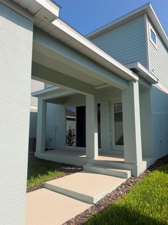 A covered patio with concrete steps leads to a sliding glass door and a side door — 16968 HAMLIN OASIS LOOP, WINTER GARDEN, FL