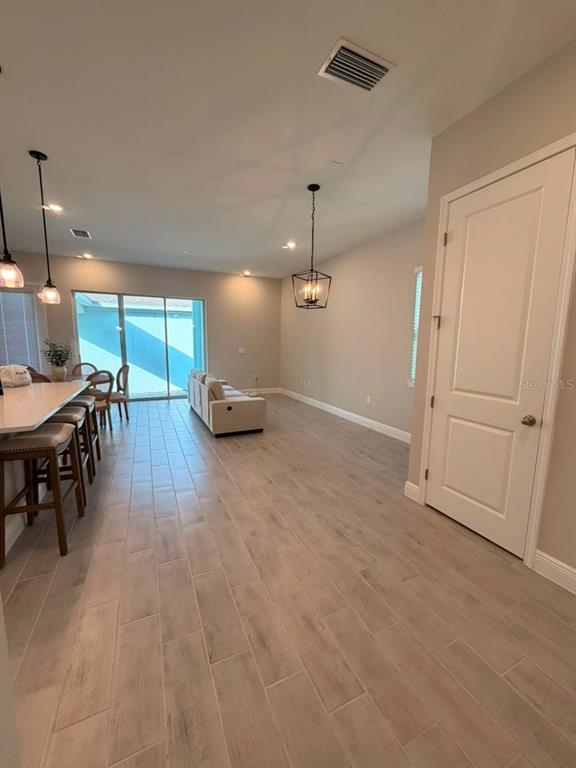 An open-concept living and dining area features light wood-look tile flooring and pendant lighting — 16968 HAMLIN OASIS LOOP, WINTER GARDEN, FL