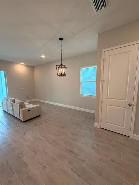 A living room features light wood-look tile flooring, a beige sofa, and a hanging lantern pendant — 16968 HAMLIN OASIS LOOP, WINTER GARDEN, FL