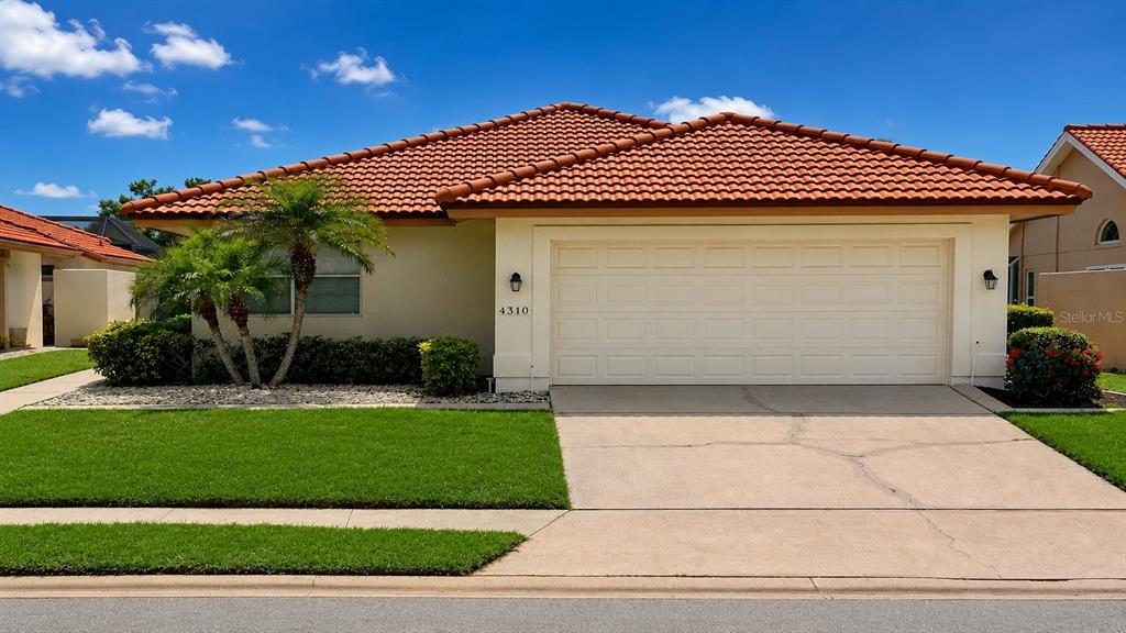 A single-story house with a terracotta tile roof, a two-car garage, and a front lawn — 4310 MURFIELD DRIVE E, BRADENTON, FL