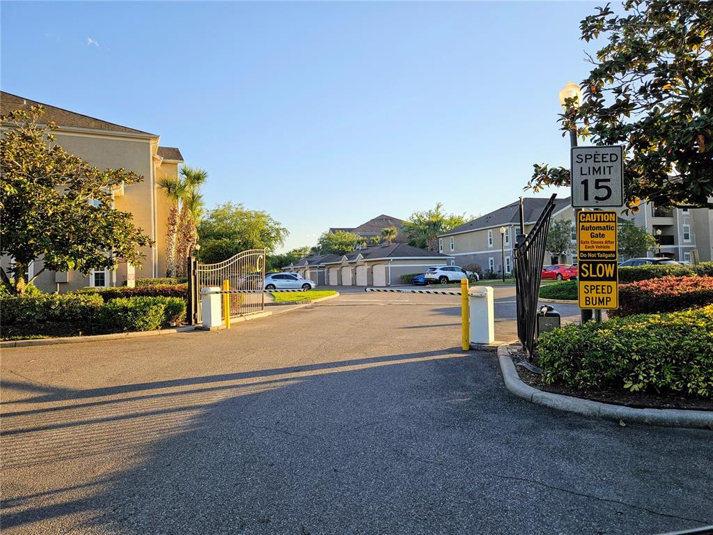 An outdoor view of an apartment complex entrance with a security gate and signage — 6548 SWISSCO DRIVE UNIT 628, ORLANDO, FL