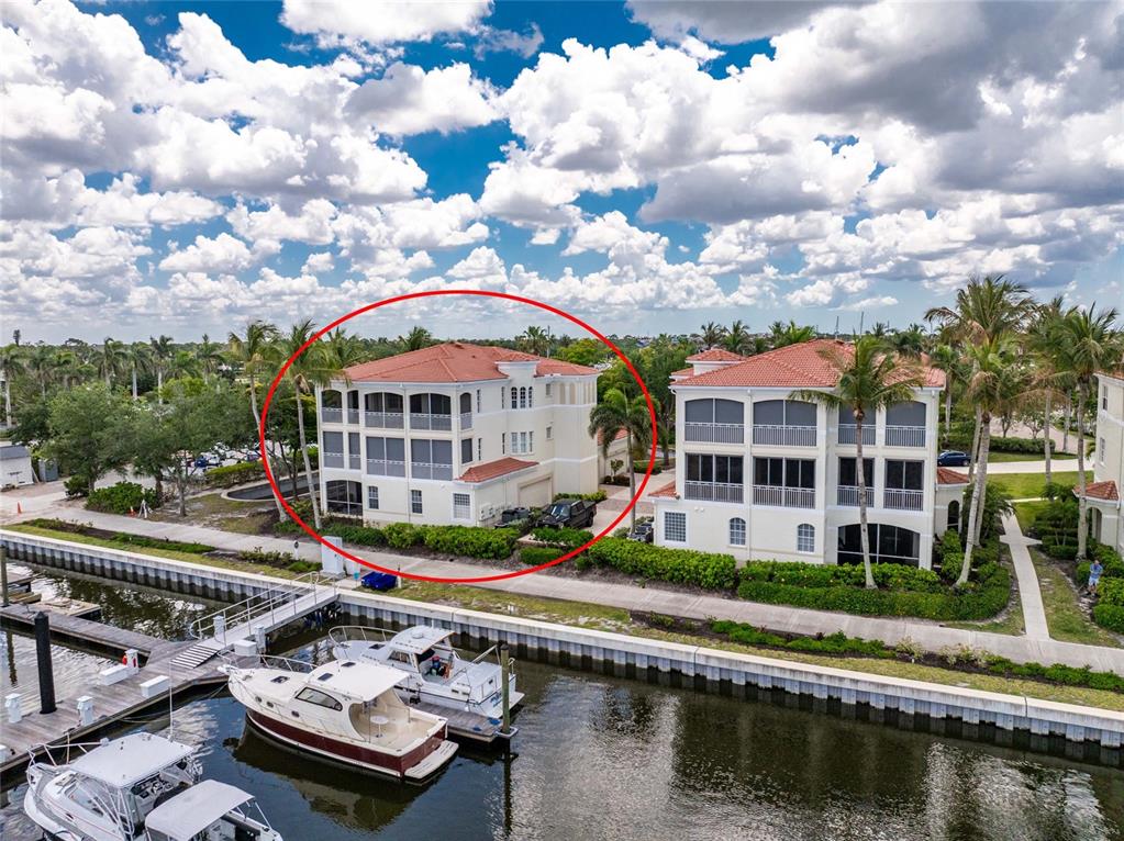 An aerial view shows a multi-story residential building with a red tile roof near a canal — 3485 SUNSET KEY CIRCLE UNIT 101, PUNTA GORDA, FL