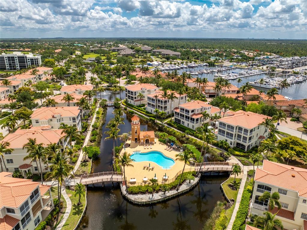 An aerial view of a residential complex with a central pool, canal, and boat docks — 3485 SUNSET KEY CIRCLE UNIT 101, PUNTA GORDA, FL