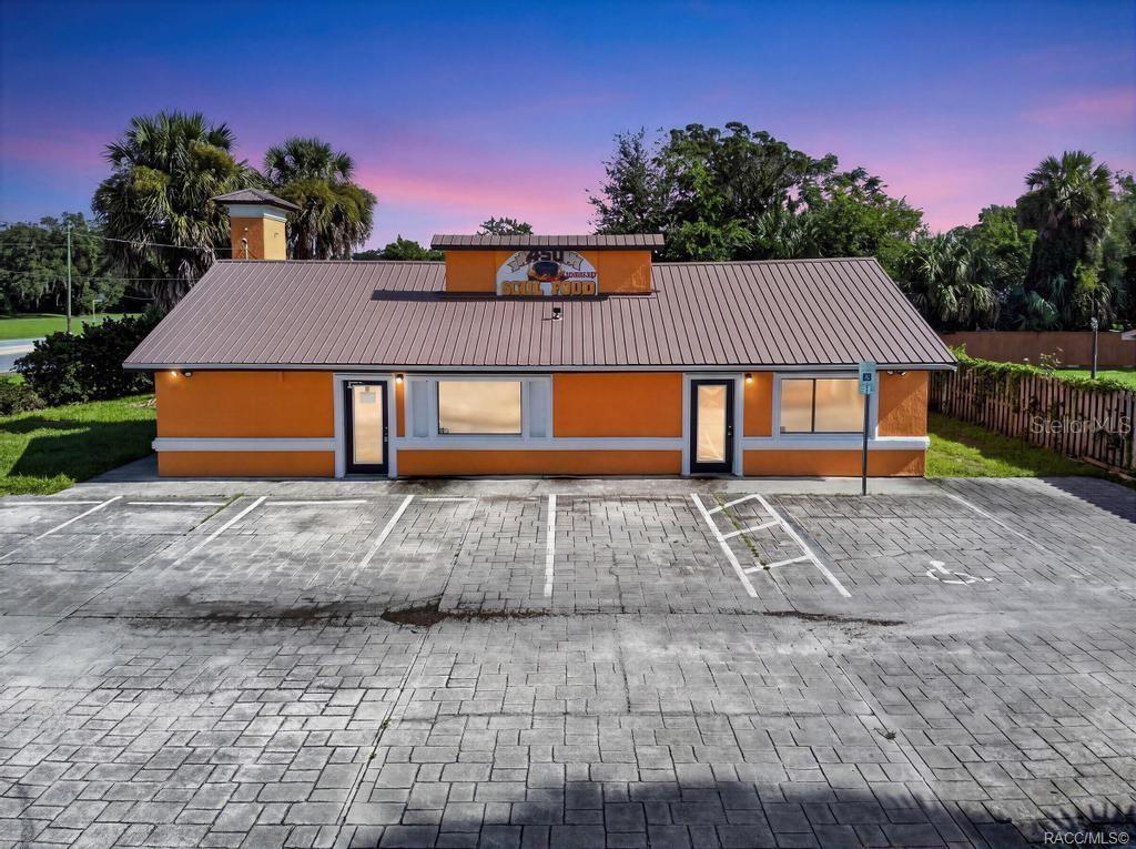 An orange commercial building with a metal roof and a paved parking lot in front — 102 PHILLIPS DAIRY ROAD, PALATKA, FL