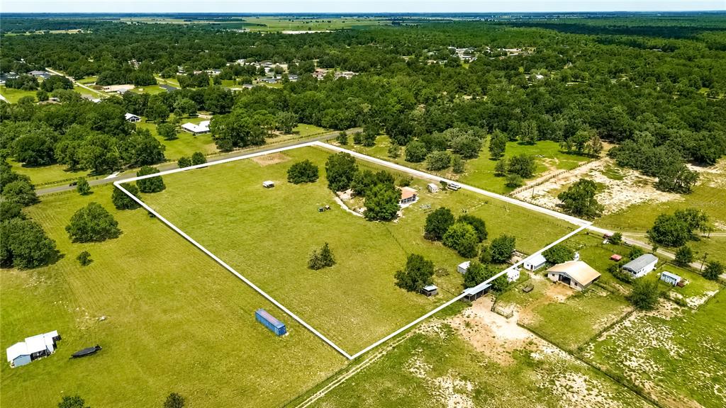 An aerial view shows a large, fenced grassy lot with a house and several outbuildings — 10525 SW 129TH TERRACE ROAD, DUNNELLON, FL