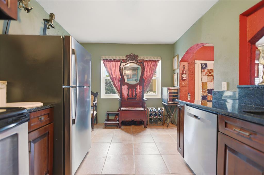 A kitchen features stainless steel appliances, dark wood cabinets, tile flooring, and a decorative wooden chair — 120 VALENCIA ROAD, ROCKLEDGE, FL