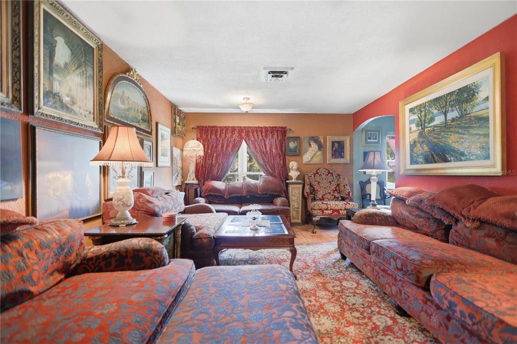 A living room features red patterned furniture, ornate framed artwork, and a large area rug — 120 VALENCIA ROAD, ROCKLEDGE, FL