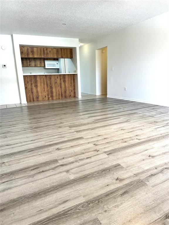 A living room with wood-look flooring leads to a kitchen featuring wood-grain cabinets and counters — 13608 S VILLAGE DRIVE UNIT 8203, TAMPA, FL