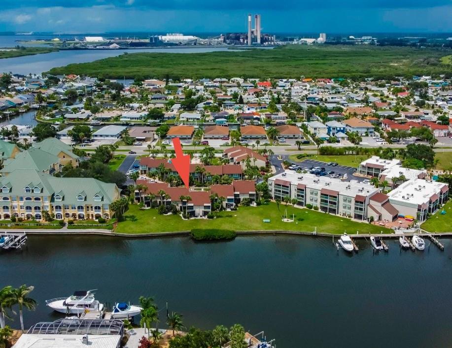 An aerial view shows a multi-story residential complex situated along a waterfront with green lawns — 1028 APOLLO BEACH BOULEVARD UNIT 11, APOLLO BEACH, FL