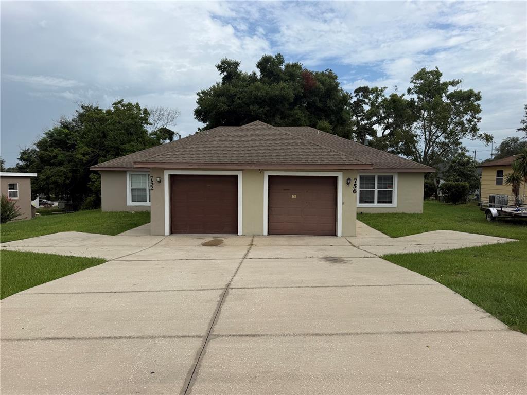 A single-story duplex with two brown garage doors and a large concrete driveway — 752 E BROOME STREET, CLERMONT, FL