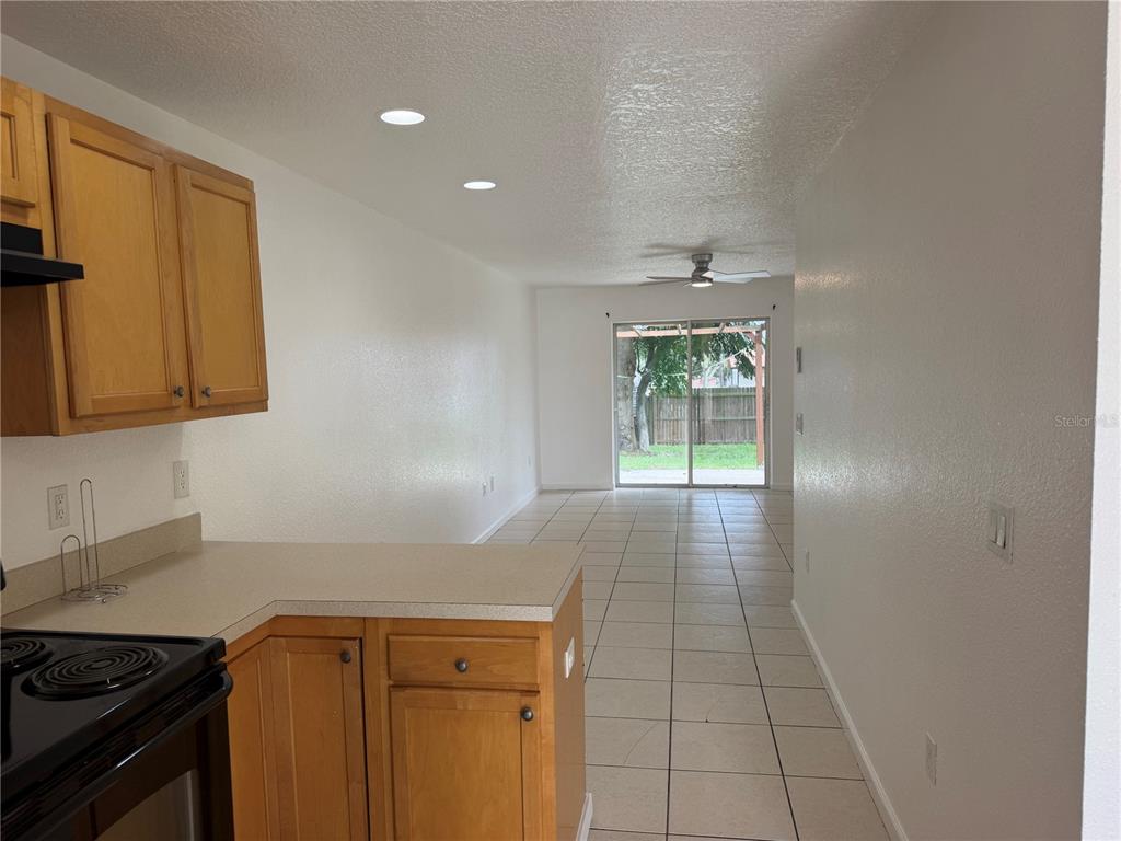 A kitchen with light wood cabinets overlooks a tiled living area with a sliding glass door — 752 E BROOME STREET, CLERMONT, FL