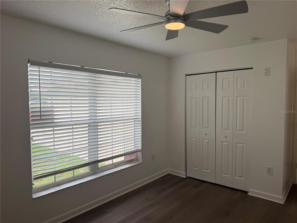 A bedroom with white walls, wood-look flooring, a ceiling fan, and a white closet — 752 E BROOME STREET, CLERMONT, FL
