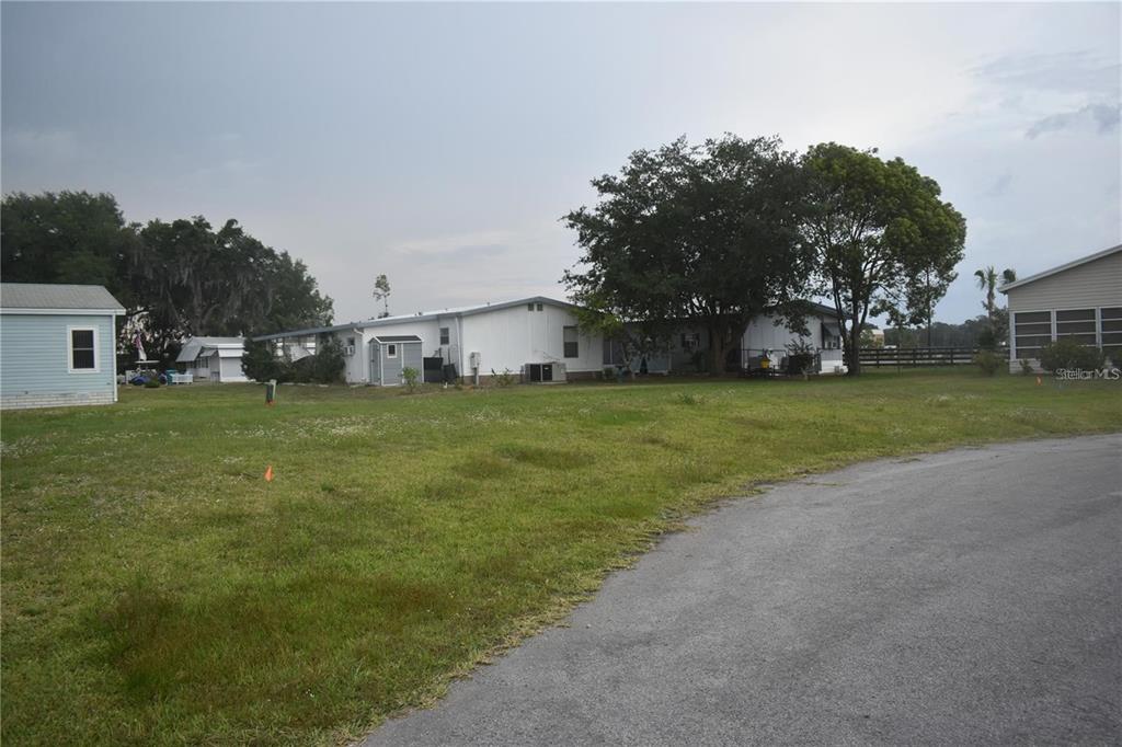 A grassy lot with several manufactured homes and trees under a cloudy sky — LOT 11 BLK D LEXINGTON CIRCLE, WILDWOOD, FL