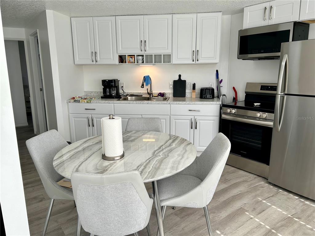 A kitchen features white cabinets, stainless steel appliances, and a round dining table with chairs — 23917 DEER ROAD, ASTOR, FL