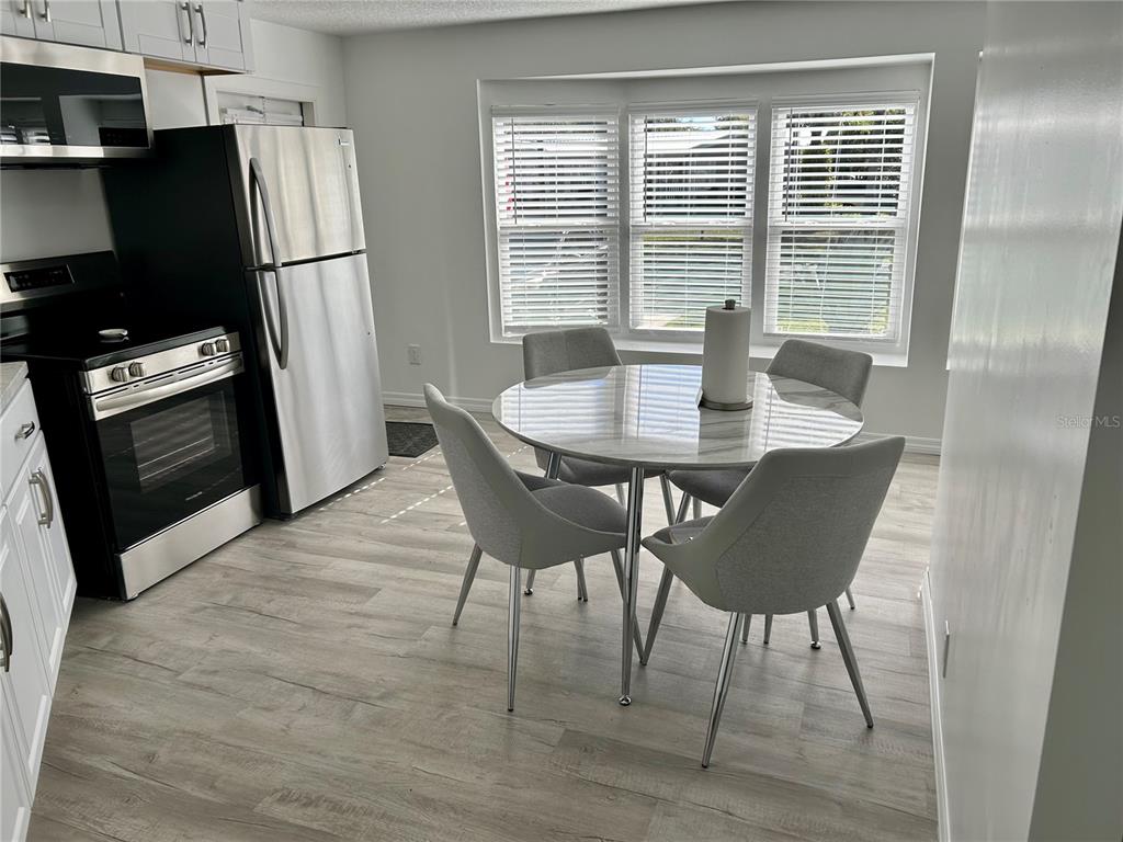 A kitchen and dining area with stainless steel appliances, light wood flooring, and a round table — 23917 DEER ROAD, ASTOR, FL