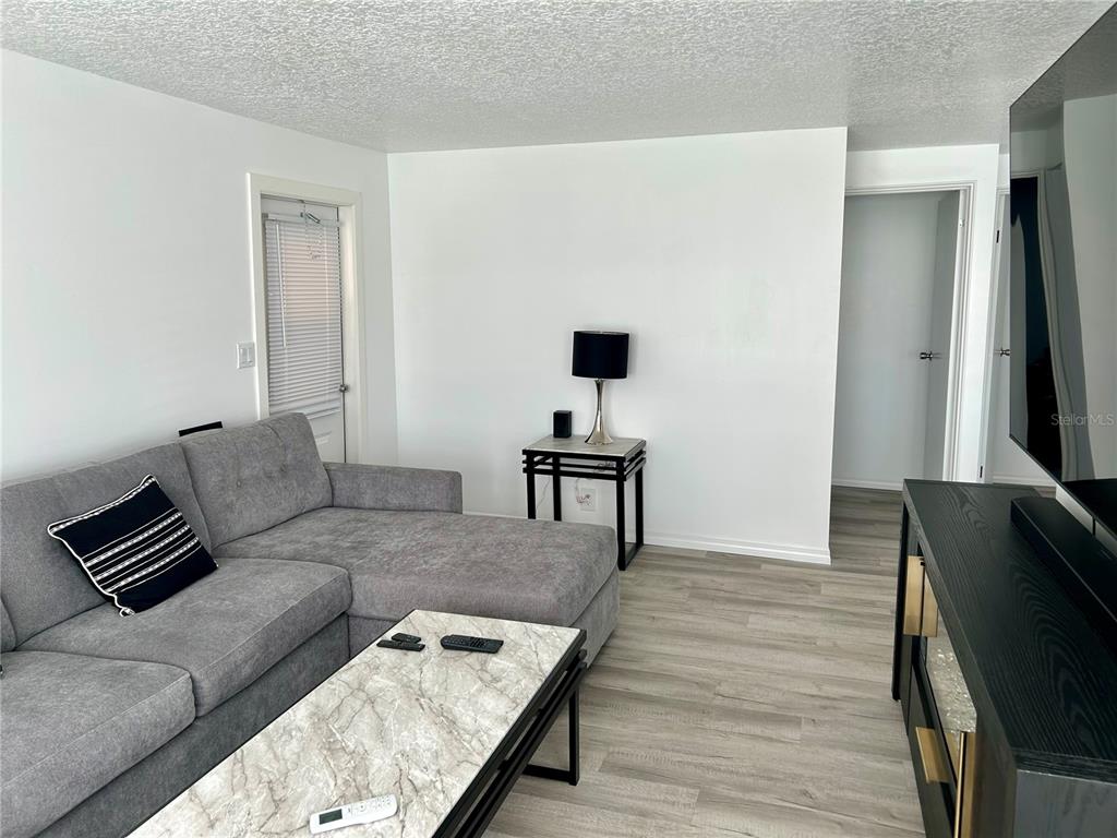 A living room features a grey sectional sofa, a marble-topped coffee table, and light flooring — 23917 DEER ROAD, ASTOR, FL