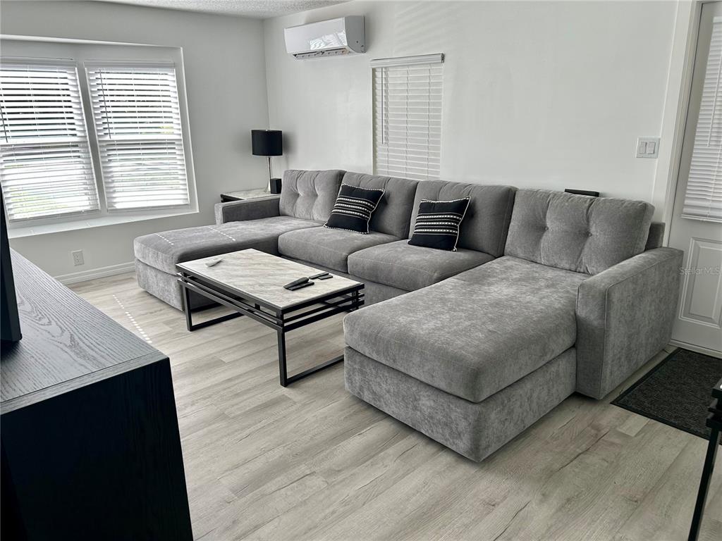 A living room features a large gray sectional sofa, a marble-topped coffee table, and light flooring — 23917 DEER ROAD, ASTOR, FL