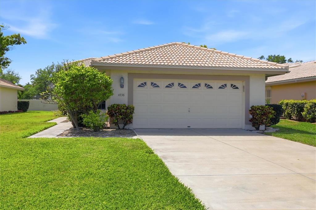 A single-story house with a beige stucco exterior, a tiled roof, and a two-car garage — 4738 DUNDEE DRIVE, BRADENTON, FL
