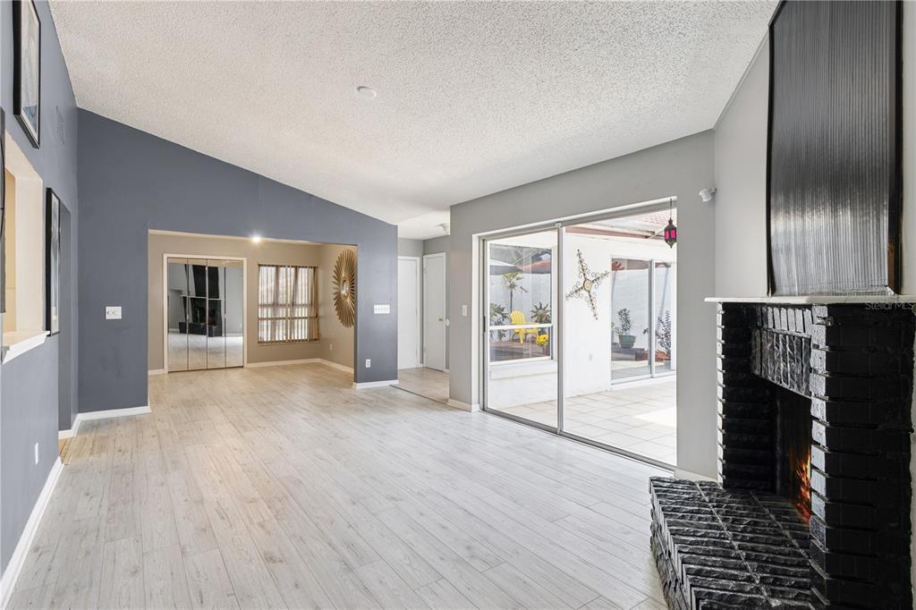 A living room features light wood-look flooring, a dark brick fireplace, and a sliding glass door — 4948 FIJI CIRCLE UNIT 3D, ORLANDO, FL