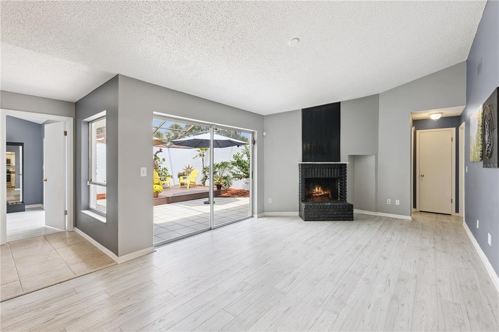 A living room with light wood flooring, a corner fireplace, and sliding doors to a patio — 4948 FIJI CIRCLE UNIT 3D, ORLANDO, FL