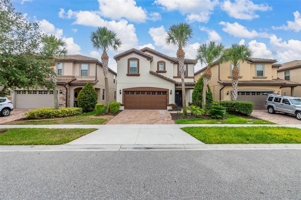 A two-story suburban house with a brown garage door and palm trees in the front — 8912 RHODES STREET, KISSIMMEE, FL