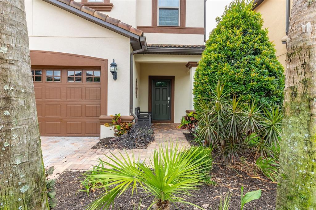 An exterior view of a house entrance featuring a garage, front door, and landscaping — 8912 RHODES STREET, KISSIMMEE, FL