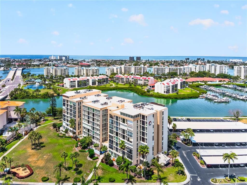 An aerial view shows a multi-story apartment complex with a swimming pool and waterfront access — 7400 SUN ISLAND DRIVE S UNIT 203, SOUTH PASADENA, FL