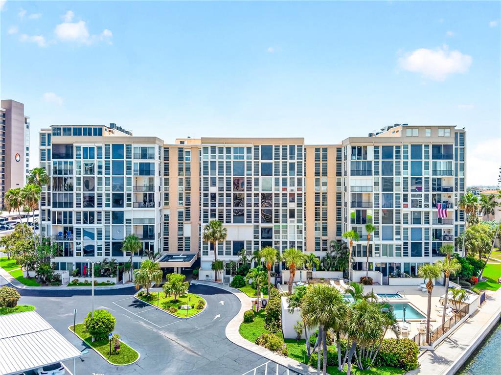 An aerial view shows a multi-story apartment complex with a pool, parking, and waterfront access — 7400 SUN ISLAND DRIVE S UNIT 203, SOUTH PASADENA, FL