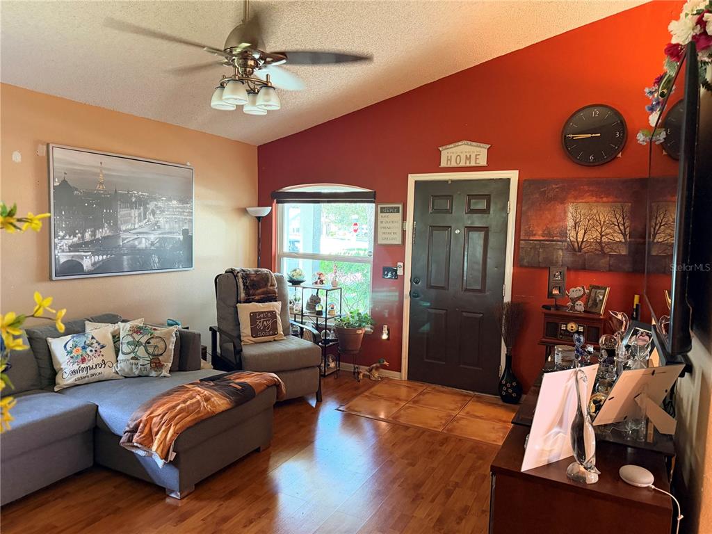 A living room features wood flooring, a ceiling fan, a gray sectional, and red walls — 6224 TABOGI TRAIL, WESLEY CHAPEL, FL