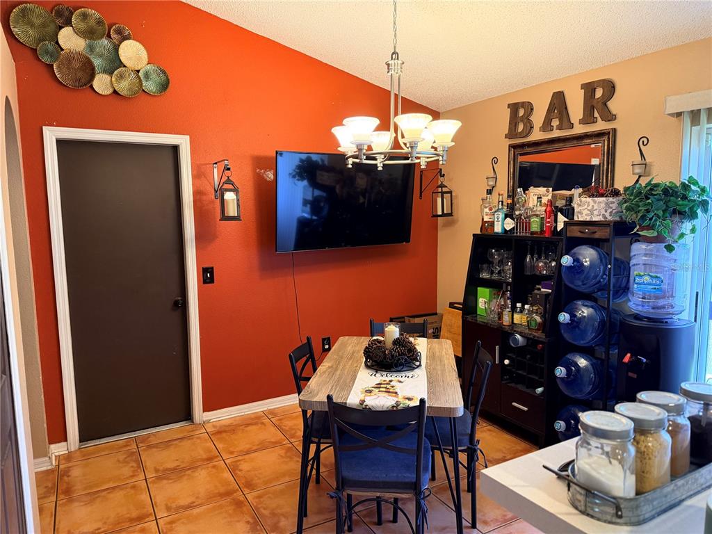 A dining room features an orange accent wall, a bar area, and a wooden table — 6224 TABOGI TRAIL, WESLEY CHAPEL, FL