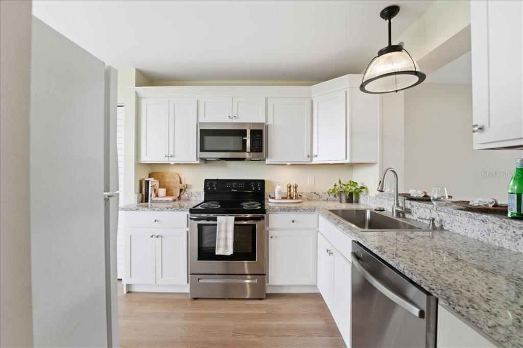 A kitchen features white cabinets, stainless steel appliances, and granite countertops — 4550 PINEBROOK CIR UNIT 506, BRADENTON, FL