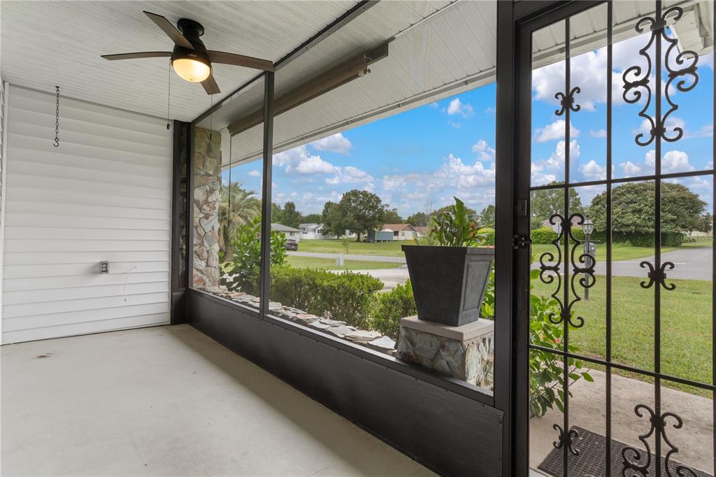 A screened-in porch with a ceiling fan, stone accents, and a decorative metal screen door — 3849 N TAMARISK AVENUE, BEVERLY HILLS, FL