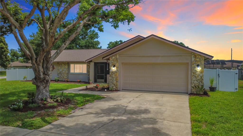 A single-story house with a stone-accented facade, a two-car garage, and a large front tree — 8654 ALEGRE CIRCLE, ORLANDO, FL