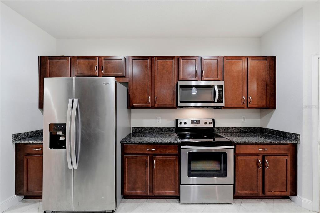 A kitchen features stainless steel appliances, dark wood cabinets, and granite countertops — 11752 CAMBIUM CROWN DRIVE, RIVERVIEW, FL