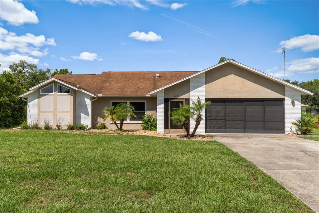 A single-story house with a brown roof, tan stucco walls, and a two-car garage — 2285 GODFREY AVENUE, SPRING HILL, FL